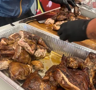 Pans of smoked BBQ chicken being cut and served
